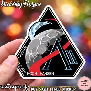 Może przedstawiać: Czarna, biała i czerwona naklejka z trójkątnym wzorem przedstawiającym księżyc, Ziemię i literę "A". Naklejka zawiera nazwiska "WISEMAN", "GLOVER", "KOCH" i "HANSEN". Widoczny jest również tekst "waterproof".