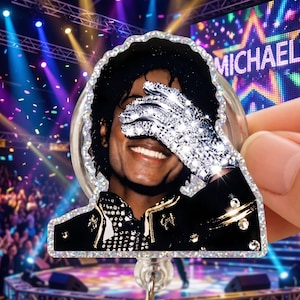 Könnte beinhalten: Ein Ausweis-Rollhalter mit einem lächelnden Porträt von Michael Jackson, der seine Augen mit einem funkelnden Handschuh bedeckt. Der Hintergrund zeigt eine Bühne mit dem Namen "MICHAEL" in Lichtern. Die Rolle hat einen glitzernden Rand.