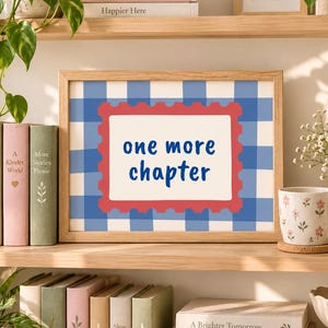 May include: A framed rectangular print featuring a blue and white gingham pattern background with a central white rectangle bordered by a red scalloped edge. The text "one more chapter" is printed in blue in the center of the white rectangle.