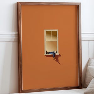 Puede incluir: Una impresión artística enmarcada que representa a una persona descansando en una ventana. La obra de arte tiene un estilo minimalista con una persona con vaqueros azules y una camisa azul. El fondo es de color naranja liso y el marco es marrón.