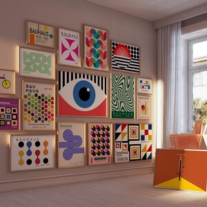 May include: A wall gallery featuring 14 framed prints with geometric designs and the text "Bauhaus" in various colors and fonts. The prints are arranged in a grid pattern and include abstract shapes, circles, and lines.
