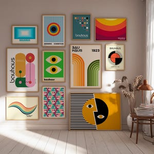 May include: A wall gallery featuring nine framed prints with geometric designs in various colors, including yellow, orange, red, green, blue, and black. The prints feature the text "Bauhaus" and "Bauhaus Exhibition".