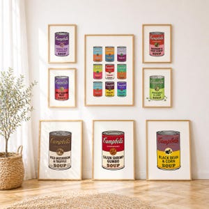 May include: A gallery wall arrangement of eight framed prints featuring various Campbell's soup cans. The prints display colorful labels with text including Purple Yam & Coconut, Spicy Korean Beef, Beetroot & Goat Cheese, Avocado & Lime, Wild Mushroom & Truffle, Cajun Shrimp Gumbo, and Black Bean & Corn.