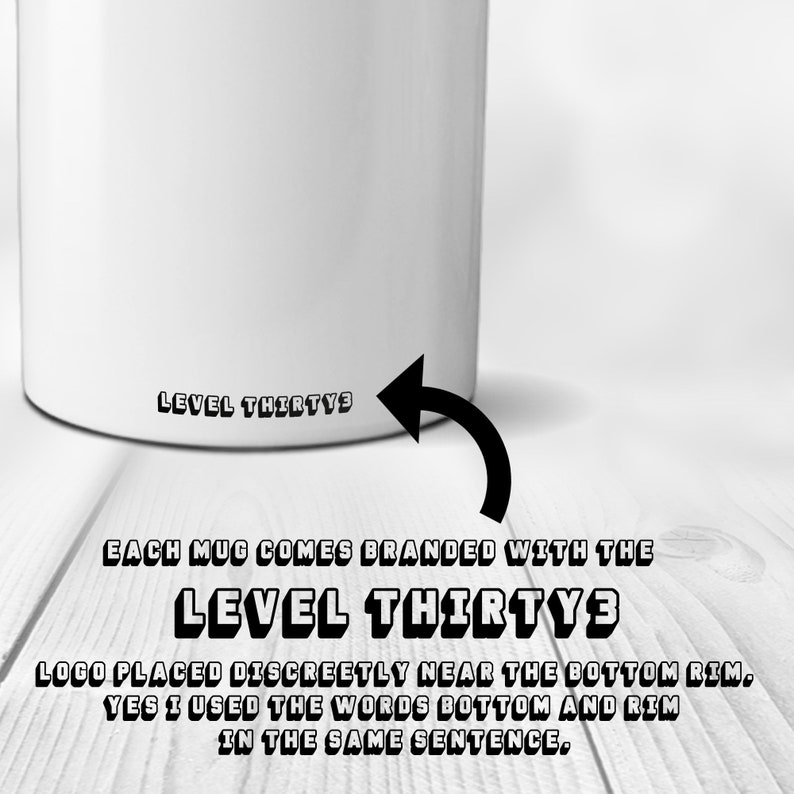 May include: White ceramic mug with black text that reads "LEVEL THIRTY3" on the bottom. The text is in a bold, blocky font. The mug is sitting on a wooden surface.