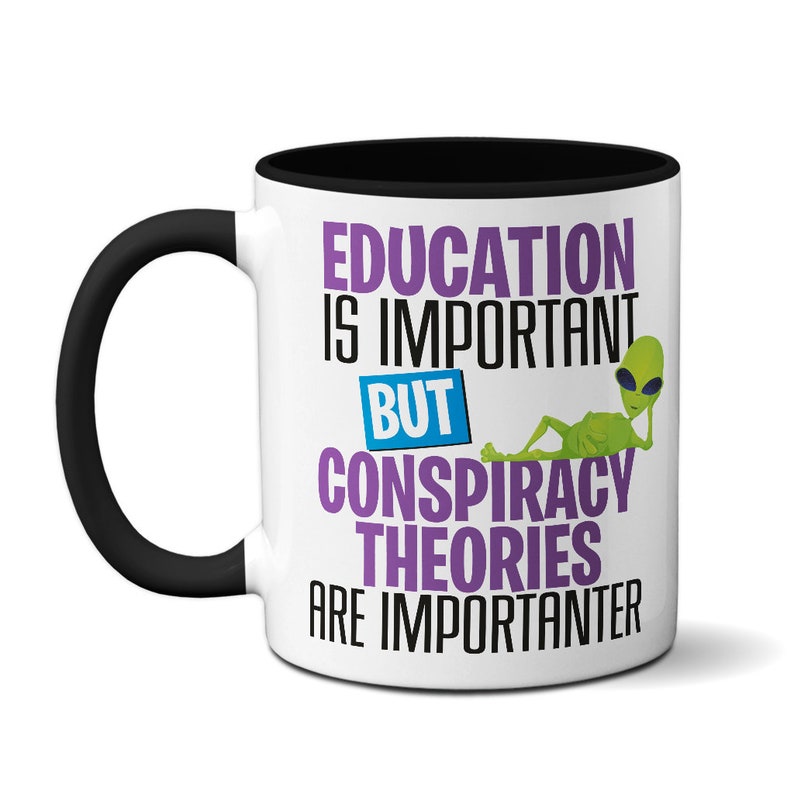 May include: White ceramic coffee mug with a black rim and handle. The mug features a purple and black graphic that reads "Education is important but conspiracy theories are importanter". A green alien with sunglasses is lying on the text.