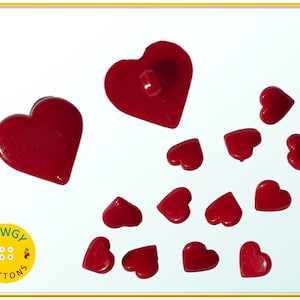 May include: A set of 14 red heart-shaped buttons. The buttons are made of plastic and have a smooth, glossy finish. The buttons are in various sizes, with the largest button being about 1 inch in diameter. The buttons are arranged in a random pattern on a white background.