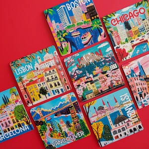 Op de afbeelding: Een verzameling kleurrijke vierkante onderzetters met stadsgezichten. Onderzetters bevatten illustraties van Boston, Chicago, Lissabon, Japan, Barcelona, Vancouver en Istanbul. Elke onderzetter heeft de stadsnaam in een vetgedrukte letter.