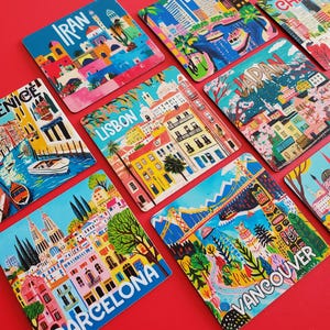 Op de afbeelding: Een verzameling kleurrijke vierkante onderzetters met stadsgezichten. Elke onderzetter toont een andere stad, waaronder Boston, Chicago en Barcelona, met levendige illustraties en stadsnamen. De onderzetters zijn gerangschikt op een rode ondergrond.