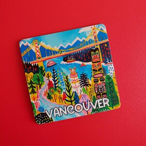 Op de afbeelding: Een kleurrijke vierkante magneet met een gestileerde illustratie van Vancouver, Canada. Het ontwerp omvat een brug, een totempaal en de naam van de stad in witte letters tegen een levendig landschap van blauw, groen en geel.