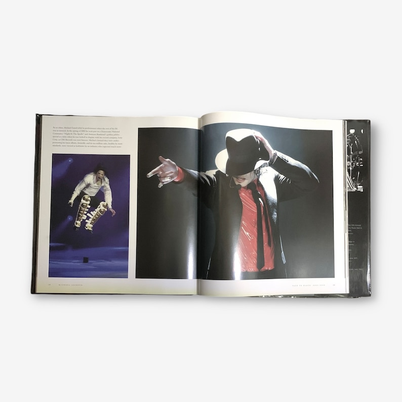 K&ouml;nnte beinhalten: Ein offenes Buch mit zwei Fotos von Michael Jackson. Das linke Foto zeigt ihn beim Springen in der Luft, er tr&auml;gt ein wei&szlig;es Hemd, eine schwarze Hose und einen goldenen G&uuml;rtel. Das rechte Foto zeigt ihn in einer schwarzen Jacke, einem roten Hemd und einem schwarzen Hut. Das Buch hat den Text "Michael Jackson" auf dem Cover.