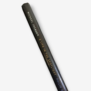 K&ouml;nnte beinhalten: Schwarzer Buchr&uuml;cken mit goldener Aufschrift "MICHAEL JACKSON - A LIFE IN THE SPOTLIGHT - PHILIP D"