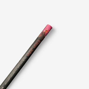 May include: A rolled-up poster featuring a photo of Elton John, a legendary performer. The poster is black with orange text that reads "Elton John The life and music of a legendary performer".