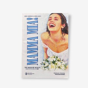 Peut inclure: Un programme de théâtre vintage pour la comédie musicale "Mamma Mia !" avec une femme souriante en robe blanche tenant un bouquet de fleurs blanches. Le titre "MAMMA MIA !" est en grandes lettres bleues. Le programme comprend également le texte "THE SMASH HIT MUSICAL BASED ON THE SONGS OF ABBA."