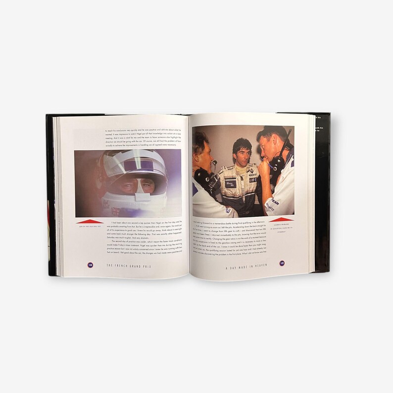 May include: An open book with a black cover and white pages. The book features a photo of a race car driver wearing a helmet and a photo of three men talking. The text on the page reads "The French Grand Prix" and "A Day Made in Heaven."