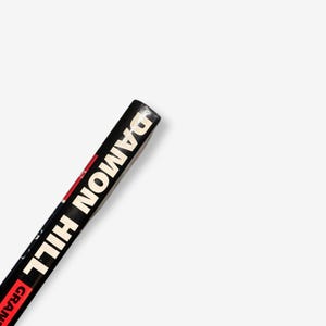 May include: Close-up of the spine of a black hardcover book with the title "Damon Hill" in white text.