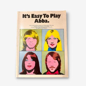 Könnte beinhalten: Ein Buchcover mit dem Titel "It's Easy To Play Abba." Das Cover zeigt ein farbenfrohes Bild im Pop-Art-Stil der vier Mitglieder der schwedischen Popgruppe Abba.