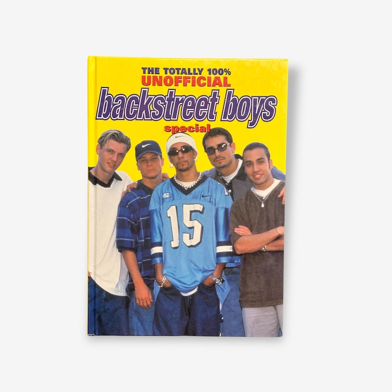 May include: A yellow book cover with the text "The Totally 100% Unofficial Backstreet Boys Special" in red and black letters. A photo of five men in a band, wearing casual clothing, is featured on the cover.