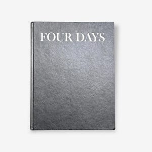 以下が含まれることがあります： 表紙に白文字で「FOUR DAYS」と書かれたグレーのハードカバーの本。本は、テクスチャ加工された表面とシンプルなデザインです。