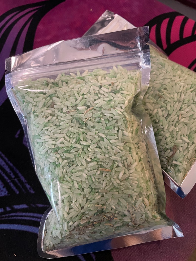 May include: Two clear, resealable plastic pouches filled with long-grain white rice that has been dyed a pale mint green color. The rice grains are mixed with small, thin, dried brown botanical pieces throughout the contents of the bags.