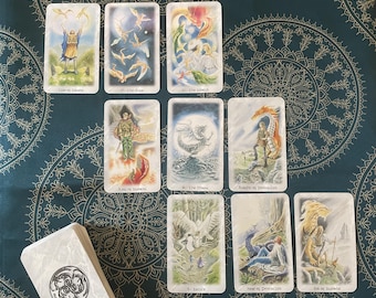 May include: A spread of tarot cards featuring illustrations of dragons, birds, and other mythical creatures. The cards are laid out in a grid pattern on a blue and gold patterned surface. The cards include "The Star", "The Moon", "Knight of Pentacles", "Nine of Pentacles", and "Six of Swords".