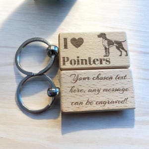 May include: Wooden keychain with two rectangular tags. The top tag features a silhouette of a dog and the text "I ♥ Pointers". The bottom tag has the text "Your chosen text here, any message can be engraved!"