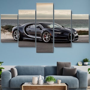 Puede incluir: Un coche deportivo Bugatti Chiron negro está aparcado en una playa con un mar azul de fondo. El coche tiene una pintura negra y plateada y un interior negro. El coche está aparcado en una playa de arena con algunas plantas de fondo.