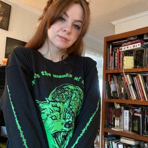 May include: Black long-sleeve shirt with a green wolf graphic and the text "Rule the woods at night".