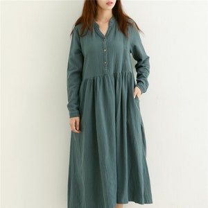 May include: A long-sleeved, teal blue, button-down dress with a gathered skirt and pockets.