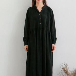 May include: A black long-sleeved dress with a button-up front and a slightly flared skirt. The dress is made of a soft, lightweight fabric and has a relaxed fit.