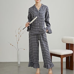 May include: A blue and white checkered pajama set with long sleeves and a ruffled hem. The top has a button-up front and a collar. The pants have a wide leg.