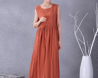May include: A sleeveless maxi dress in a terracotta color with a tie at the waist. The dress is made of a lightweight fabric and has a relaxed fit.