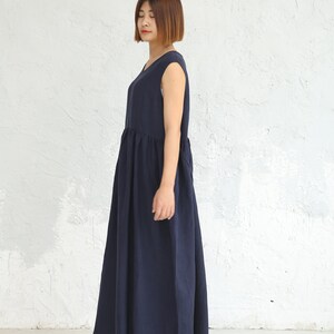 May include: A navy blue sleeveless maxi dress with a gathered waistline. The dress is made of a soft, flowing fabric.