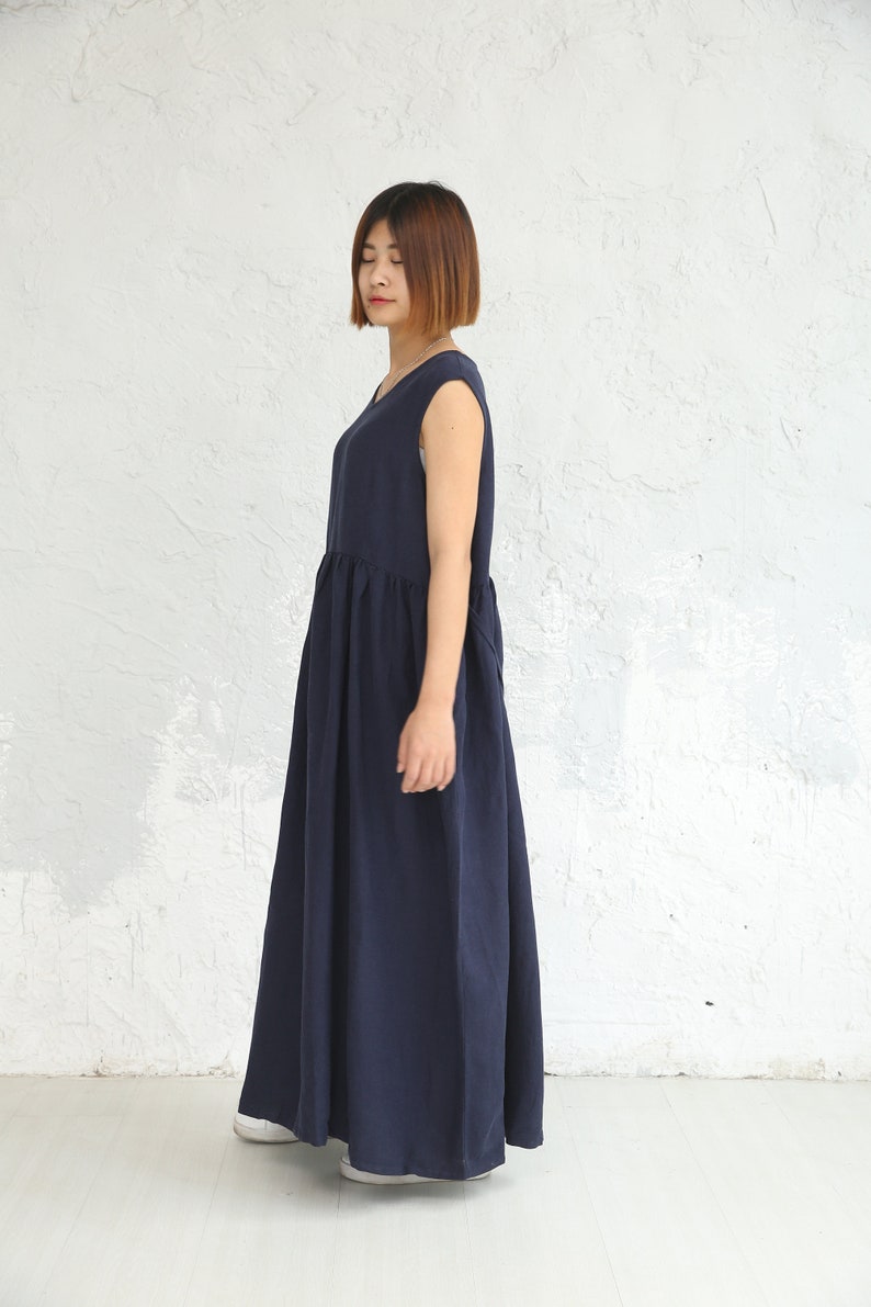 May include: A navy blue sleeveless maxi dress with a gathered waistline. The dress is made of a soft, flowing fabric.