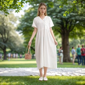 May include: A woman in a white dress holds a small wicker basket in a park setting. She is wearing white shoes and has long blonde hair.
