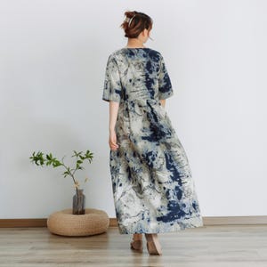 May include: A long, flowing dress with a blue and white abstract print. The dress has a v-neck and short sleeves. The dress is made of a lightweight fabric and is perfect for warm weather.