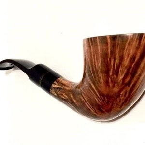 Könnte beinhalten: Eine braune Holzpfeife mit einem schwarzen Schaft. Der Kopf der Pfeife ist gebogen und hat eine Holzmaserung.