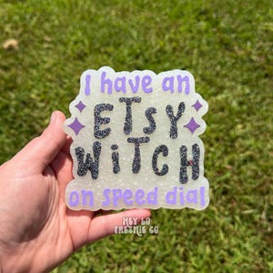 May include: A white, textured, cloud-shaped air freshener featuring the purple text 'I have an ETSY WITCH on speed dial'. The words 'ETSY WITCH' are rendered in a dark, glittery, textured font, while the remaining text is in a smooth purple.