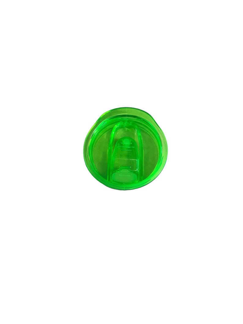 Op de afbeelding: Een transparante groene plastic deksel voor een beker of reismok. De deksel heeft een cirkelvormig ontwerp met een verhoogd midden en een schuifmechanisme om de drinktuit te openen en te sluiten. De deksel is ontworpen om morsen te voorkomen.
