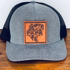 May include: A gray and black mesh trucker hat with a brown leather patch featuring a bass fish and the word "PAPA".