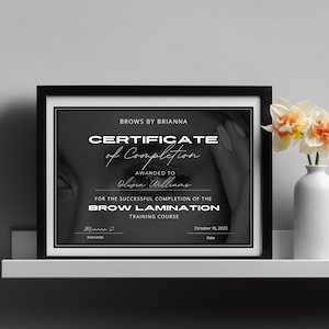 May include: Black and white certificate of completion for a Brow Lamination training course, awarded to Olivia Williams on October 18, 2023. The certificate is framed and has a black background with white text.