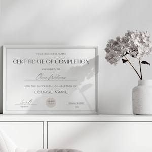 May include: A black and white certificate of completion with the text "YOUR BUSINESS NAME CERTIFICATE OF COMPLETION AWARDED TO Olivia Williams FOR THE SUCCESSFUL COMPLETION OF COURSE NAME Signature Cara B AWARD 2004 October 18, 2003 Date"
