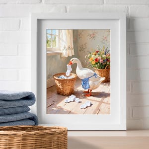 May include: A framed wall art print depicting a white goose wearing a blue and white striped apron. The goose holds a white sock in its beak near a wicker laundry basket, with scattered white socks on the floor and a basket of colorful flowers.