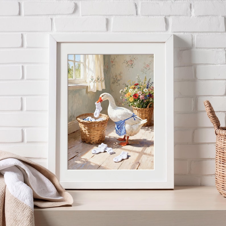 May include: Framed art print featuring a goose wearing a blue and white striped apron, holding a sock, and sorting laundry. The artwork has a vintage aesthetic, with a basket of socks and flowers in the background.