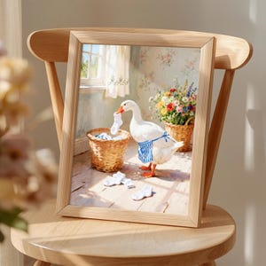 May include: A framed print featuring a white goose wearing a blue and white striped apron, holding a white sock in its beak. The scene includes a wicker laundry basket, scattered white socks on a wooden floor, and a basket of colorful flowers.