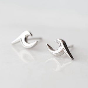 May include: A pair of silver wave-shaped stud earrings. The earrings are small and delicate, and they would make a great gift for someone who loves the sea.