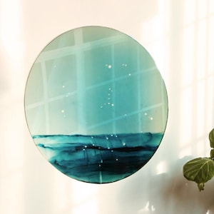 Könnte beinhalten: Ein braunes Ledersofa mit einem runden, blauen und grünen abstrakten Gemälde, das an der Wand dahinter hängt. Eine große grüne Pflanze steht in der Ecke des Raumes.