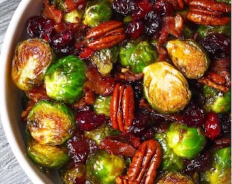 May include: A bowl of roasted Brussels sprouts with pecans, dried cranberries, and bacon. The sprouts are green and golden brown, with the bacon pieces adding a reddish-brown color. The pecans are a rich brown, and the cranberries are a deep red.