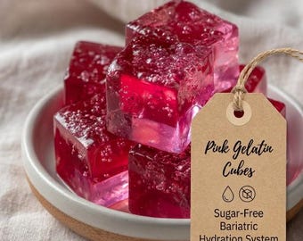 May include: A close-up of a white ceramic bowl filled with pink gelatin cubes. A brown tag with the text "Pink Gelatin Cubes" and "Sugar-Free Bariatric Hydration System" hangs from the bowl.