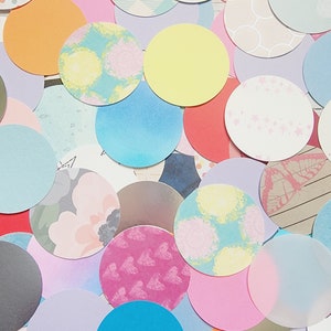 May include: Assortment of colorful patterned paper circles. The circles feature various designs, including butterflies, stars, geometric patterns, and floral motifs.