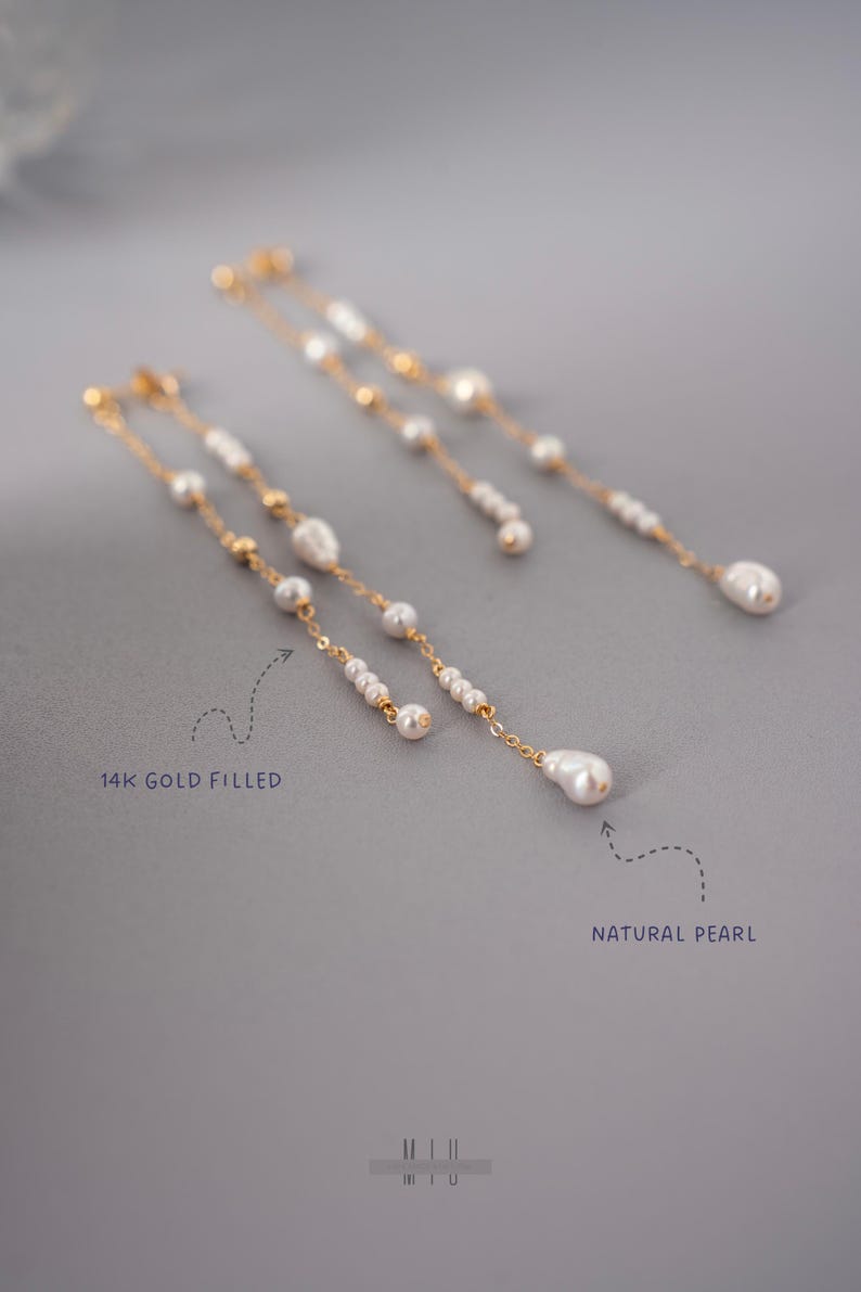 Pu&ograve; includere: Eleganti orecchini in oro riempito con perle naturali. Gli orecchini presentano un delicato design a catena con pi&ugrave; piccole perle e una perla pi&ugrave; grande a forma di goccia. Il testo "14K GOLD FILLED" e "NATURAL PEARL" sono visibili.